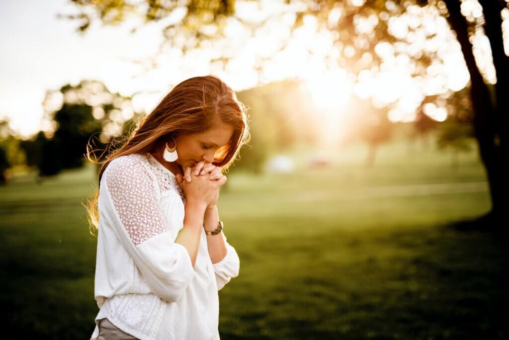 woman praying beside tree